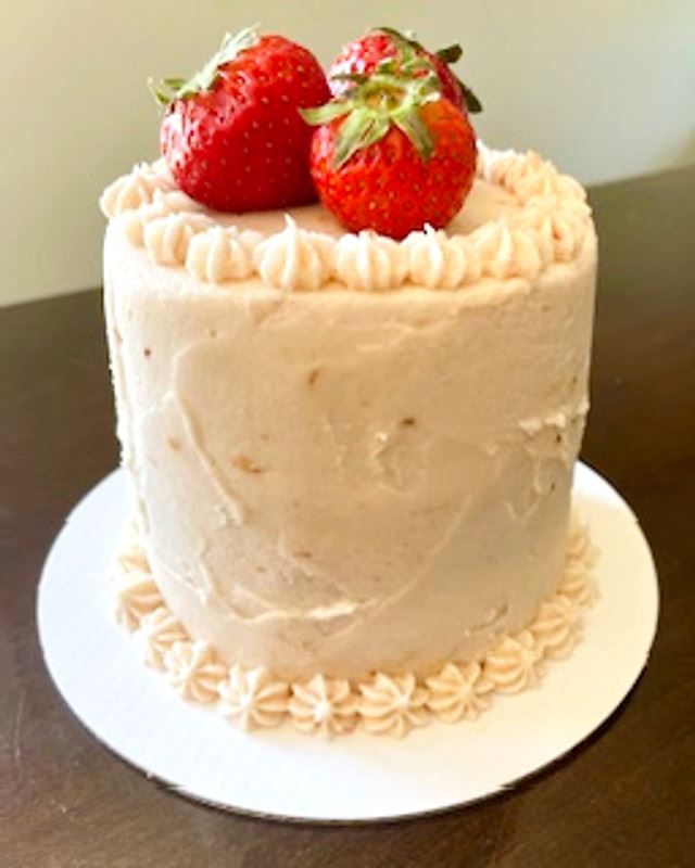 Strawberry vanilla layer cake topped with fresh strawberries