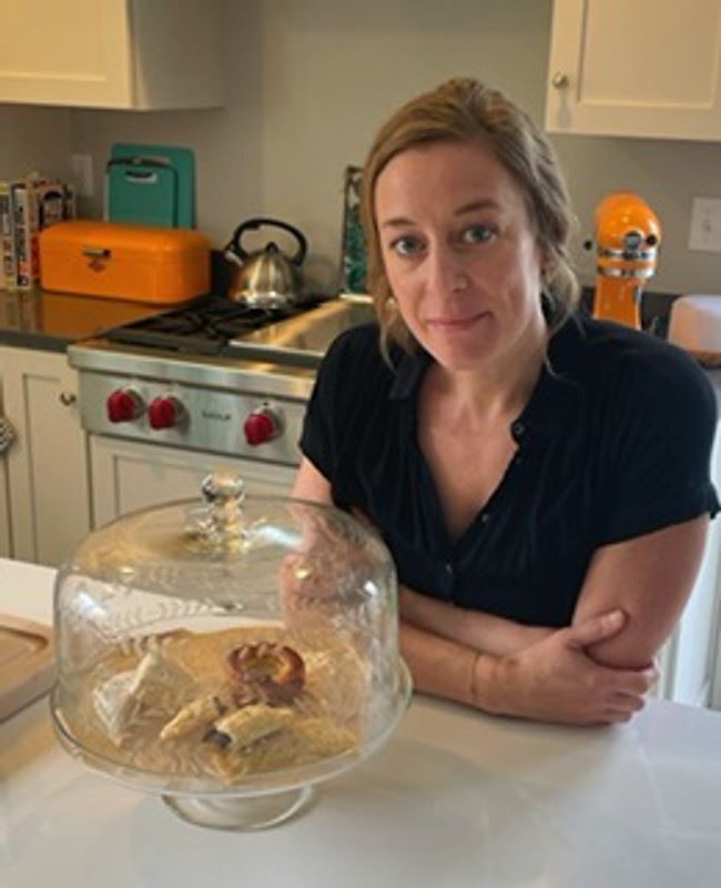 Laura in her kitchen with a cake stand of fresh pastries